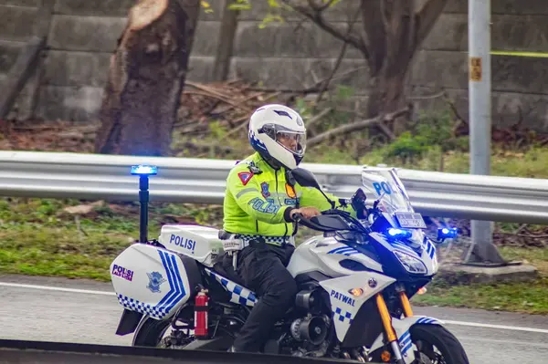 stock image a traffic policeman riding a police sports motorbike on the Surabaya toll road is carrying out an escort and turning on strobe lights along the road, Indonesia, 16 July 2024.