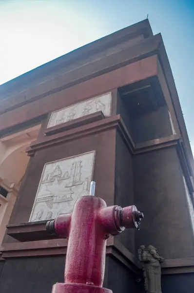 Stock image A vintage fire hydrant stands in front of a historic building with intricate carvings, offering a striking contrast between old and new.