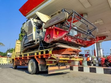 Endonezya 'da 27 Temmuz 2024' te yakıt ikmali için bir benzin istasyonunda duran büyük bir tarımsal biçerdöver kamyonla taşınıyor..