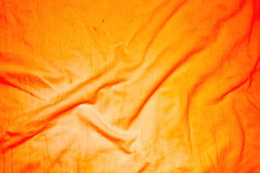 Dinamik kıvrımları ve zengin dokusu olan canlı turuncu kumaş, arka plan, moda veya tasarım unsurları için mükemmel. Işık ve gölge oyunu derinlik ve ilgi katar..