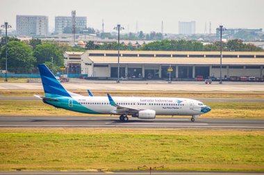 Garuda Endonezya Boeing B737 Juanda Uluslararası Havalimanı açık gökyüzü ve şehir arkaplanı, sergilenen havacılık seyahati, Surabaya, 22 Eylül 2024.