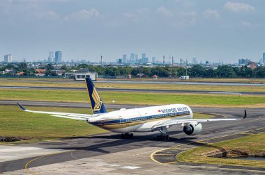 Singapur Havayolları Airbus A350 takside Juanda Uluslararası Havaalanı 'nda şehir manzarası ve açık gökyüzü arka planda, Surabaya, 22 Eylül 2024.