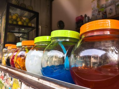 Kafenin rafındaki cam kavanozlarda renkli içecek malzemesi. Çeşitli aromalar ve canlı renkler bu malzemelerin içecekleri geliştirmek için mükemmel olmasını sağlıyor. Kafeler ve içecek dükkanları için ideal.