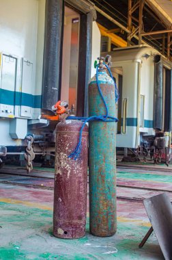 İki gaz tüpü, biri kırmızı ve biri mavi, bakım alanında bir tren vagonunun önünde yan yana durun.