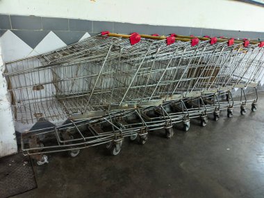 Bir süpermarkette ya da mağazada fayanslı duvara dizilmiş bir sıra alışveriş arabası organize perakende ekipmanlarını sergiliyor.