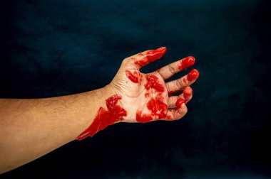 Karanlığın içinde kanlı bir avuç, şiddet ve umutsuzluğun rahatsız edici bir görüntüsü.