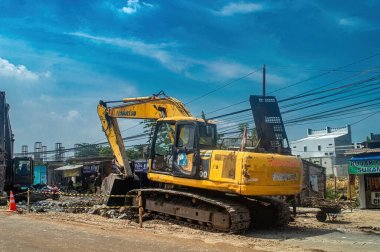 Açık mavi gökyüzünün altındaki bir inşaat alanında sarı bir Komatsu kazıcısı. İnşaat, ağır makineler ve kentsel kalkınma temaları için ideal, Endonezya, 31 Ekim 2024