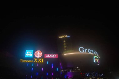 A vibrant night scene of Gressmall in Gresik, Indonesia, featuring illuminated signs of various businesses. The colorful lights create a lively atmosphere, Indonesia, 4 November 2024. clipart