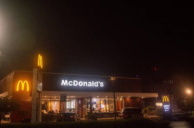 Geceleri parlak ışıklı McDonald 's restoranı görünür bir tabela ve sürüş ile, ikonik altın kemerler, Endonezya, 4 Kasım 2024.