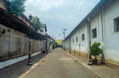 Her iki tarafında da sokak lambaları, saksı bitkileri ve açık bir gökyüzü olan 16 Kasım 2024 'te Endonezya' nın bulunduğu sessiz ve dar bir ara sokak.
