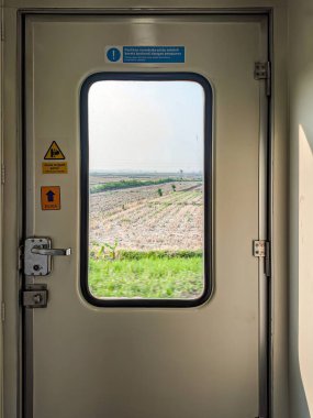 Tren kapısının penceresinden 16 Kasım 2024 'te Endonezya' nın yeşillik ve tarlalarının manzarasını gösteren bir manzara.