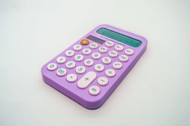 Beyaz arka planda pembe düğmeleri olan canlı mor bir hesap makinesi. Hesap makinesi ekranında sayıları gösterir ve temel aritmetik fonksiyonları gösterir, bu da onu günlük hesaplamalar için ideal kılar.
