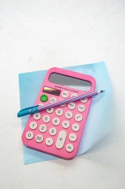 Mavi kağıt üzerinde bir kalem ile pembe hesap makinesi, okula dönüş veya ofis malzemeleri kavramları için idealdir