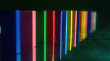 Sıraya dizilmiş renkli ahşap bloklar parlak bir yüzeye yansıyarak canlı ve görsel olarak çekici bir desen oluşturuyor.