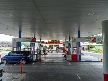 Birden fazla yakıt pompası olan Pertamina benzin istasyonu, mavi bir araba ve Endonezya 'da yürüyen biri, 2 Şubat 2025. İstasyon Pertamax, Pertalite ve Dexlite yakıtları sunuyor.