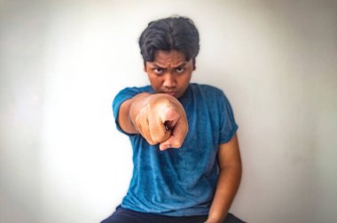 Mavi gömlekli bir adam şüpheli bir ifadeyle doğrudan kameraya bakıyor. Bağlanma ve odaklanma hissi yaratıyor. Düz beyaz arkaplan konuyu vurguluyor