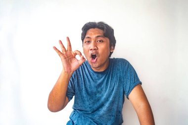 Mavi gömlekli bir adam beyaz bir arka plana el hareketi yapıyor. Görüntü basit ve net, bunu reklamlar, bloglar veya sosyal medya gibi çeşitli kullanımlar için uygun kılıyor.