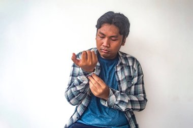 Mavi gömlekli ve ekose ceketli bir adam kolunun manşetini düzeltiyor. Görüntü sıradan bir anı yakalıyor, günlük moda ve kişisel tımarın altını çiziyor