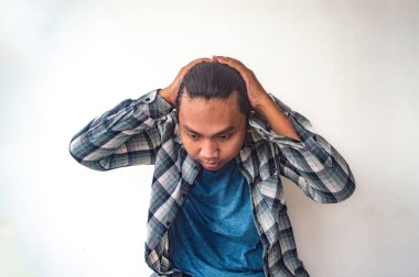 Ekose gömlekli ve mavi tişörtlü bir adam iki eliyle başını tutuyor. Pişmanlık ya da hüsran göstergesi olarak. Düz beyaz arka plan onun jestini vurguluyor.