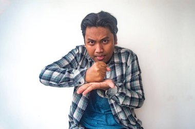 Ekose gömlekli bir adam bir eli yumruklu, diğer eli açık bir jest yapıyor. Avuç içlerine vuruyormuş gibi. Jest bir kararlılık ya da kararlılık hissi veriyor.