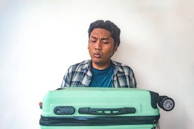 Ekose gömlekli ve mavi tişörtlü bir adam iki eliyle başını tutuyor, şaşırdığını ya da şaşırdığını ifade ediyor. Düz beyaz arka plan onun jestini vurguluyor.