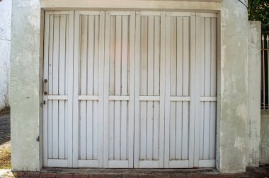 Eski beyaz ahşap katlanır garaj kapıları eskimiş bir görünüme sahip, eskimiş beton çerçeve, arka plan veya kentsel sahneler için mükemmel.
