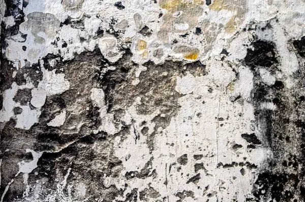 Şiddetli yıpranmış bir duvara yakın çekim, soyulmuş boyalar, koyu lekeler ve kaba doku, soyut, grunge veya çürüyen arka planlar için ideal.