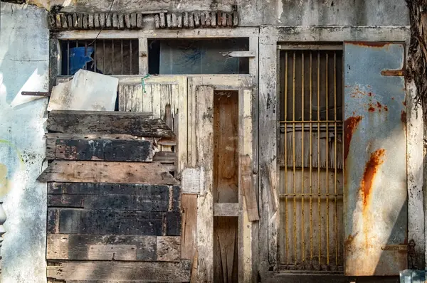 Harap olmuş ahşap kulübe kapısı, yıpranmış gecekondu mahallesi paslı metaller, eski iskeleler ve haşin güneş ışığıyla yıpranmış dokular.