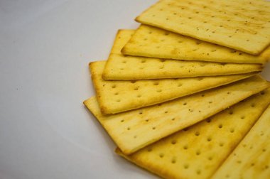 Birkaç altın, dikdörtgen krakerin yakın görüntüsü parlak beyaz bir yüzeye yayıldı. Yemek blogları, abur cubur reklamları ya da mutfak sunumları için mükemmel.