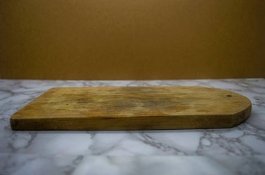 Gri mermer bir yüzey üzerinde dinlenen kırsal ahşap kesim tahtasının yer aldığı çok yönlü bir sahne, düz kahverengi arkaplan, gıda sunumu için temiz ve topraksı bir alan ya da mutfak temalı