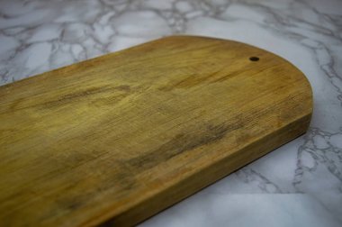 İyi giyimli ahşap bir kesme tahtasının dokusu, farklı bir delik, sofistike gri ve beyaz mermer yüzey üzerinde dinleniyor, kırsal veya aşçılık arka planları için mükemmel