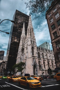 Yellow and Green Taxis passing by St. Patrick's Cathedral on Fifth Avenue - Manhattan, New York City clipart