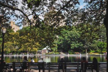 Central Park, New York 'ta, Manhattan' da konservatuar suyunda dinlenen insanlar.