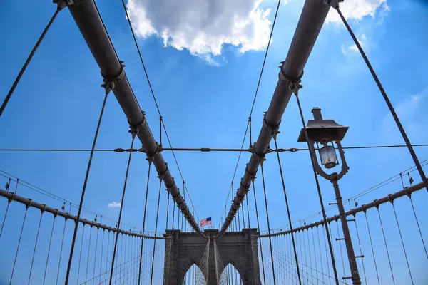 Brooklyn Köprüsü 'nün Karmaşık Askı Kabloları Ağı' nda Amerikan Bayrağı kulelerinden birinin tepesinde sergilenmektedir: Manhattan, New York