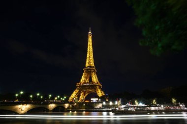 Eiffel Kulesi Paris, Fransa 'da Seine nehrinin üzerinde gece aydınlandı.