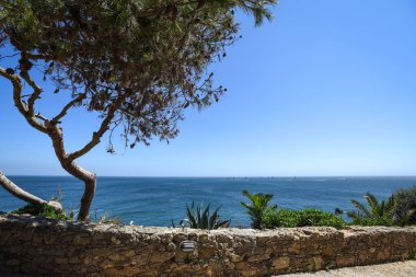 Portekiz 'in Cascais şehrinde taş duvarı olan manzaralı kıyı manzarası.