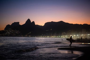 Sörfçü Siluet ve Şehir Işıkları ile Ipanema Sahili 'nde Alacakaranlık Sahnesi - Rio de Janeiro, Brezilya