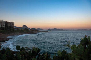 Praia do Diabo ve Sugarloaf Dağı Günbatımında Pedra do Arpoador 'dan görüldü - Rio de Janeiro, Brezilya