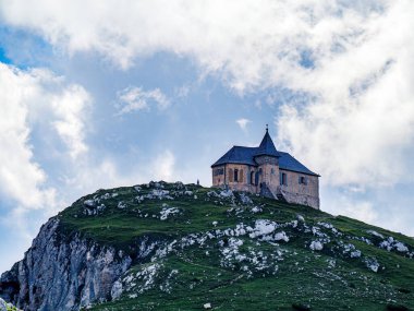 Dağ başı kilisesi Maria am Stein Dobratsch Dağı 'nın tepesinde, Avusturya, Carinthia' da, seyyahların silueti bulutlu gökyüzü.