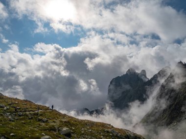 Tatra Dağları 'ndaki bir dağ yolunda yürüyüşçüler, güzel bulutlar ve mavi gökyüzü arasında.