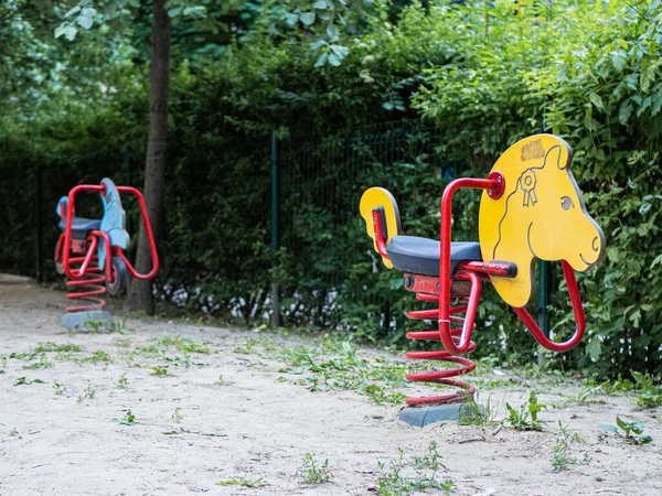 stock image Yellow horse and blue motorbike spring swing toys at a sandy green suburb playground