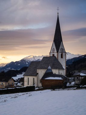 Alpler köyündeki eski bir Avustralya kilisesinin kış batımı manzarası, karlı dağlar, Wallfahrtskirche Maria Schnee Matzelsdorf, Carinthia, Avusturya