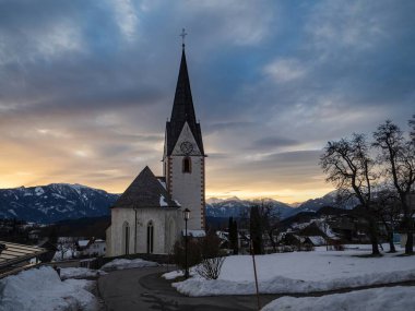 Alpler köyündeki eski bir Avustralya kilisesinin kış batımı manzarası, karlı dağlar, Wallfahrtskirche Maria Schnee Matzelsdorf, Carinthia, Avusturya