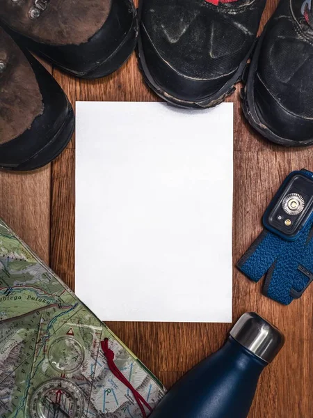 Adventure hiking exploration flat lay mockup with blank paper, headlamp, hiking boots, map, compass