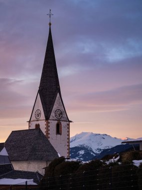Dağlardaki köy kilisesi, kışın Noel manzarası, kar dağları, gün batımı, renkli gökyüzü, Wallfahrtskirche Maria Schnee Matzelsdorf, Carinthia, Avusturya