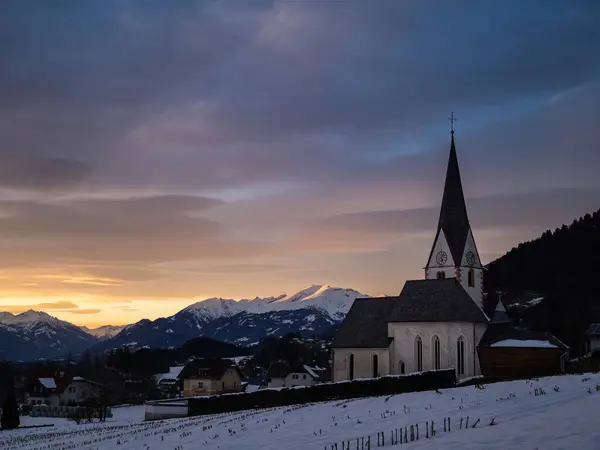 Village church in the mountains, winter christmas landscape, snow mountains, sunset, colorful sky, Wallfahrtskirche Maria Schnee Matzelsdorf, Carinthia, Austria