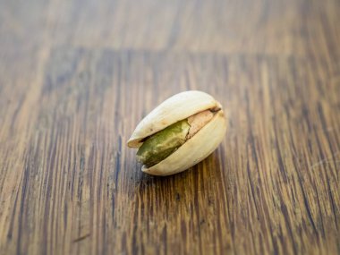 Ahşap bir masa yüzeyinde tek bir kabuklu fıstığın yakın görüntüsü.