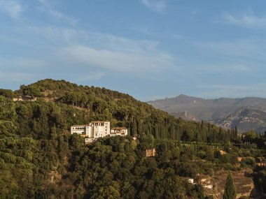 Granada, Endülüs, İspanya 'daki Albaicin bahçeleri ve yazın günbatımında arka planda Sierra Nevada dağı, yumuşak altın ışık, bulutlu gökyüzü