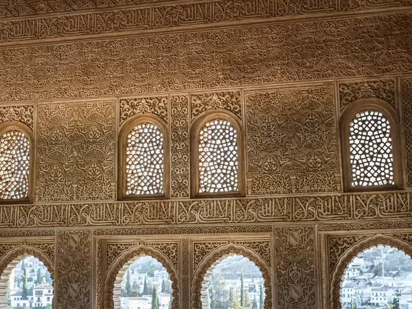 Arabic carved stone arabesque design over windows in the Alhambra palace of Granada, Andalusia, Islamic calligraphy, design architecture, decoration