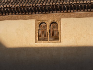 Duvara güneş ışığı ve Endülüs 'te ünlü bir Arap sarayı olan Alhambra' nın oymalı penceresi oymalı duvarlara ışık ve gölge saçıyor.